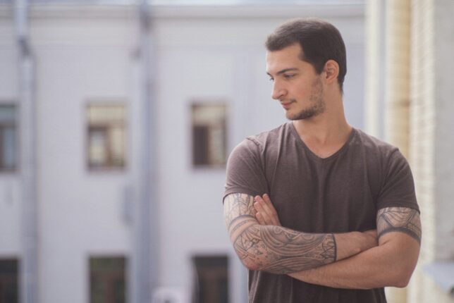 a man with tattoos standing in front of a building